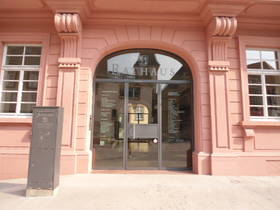 Eingang in das Alte Rathaus unter Rundbogen. Nach hinten versetzte Glastüre. Davor ansteigender Gehweg bis zum Haus.
